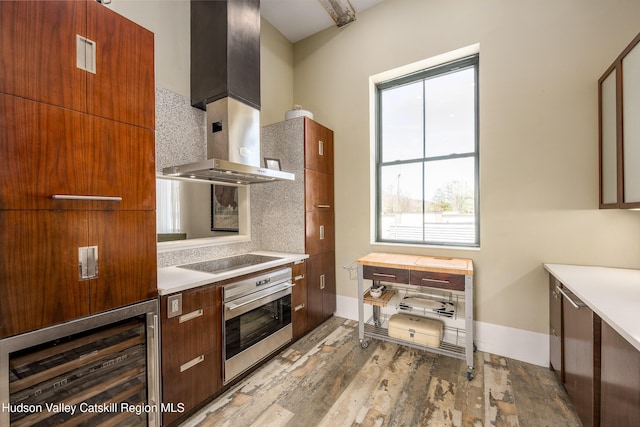 81 N Main St, Ellenville, NY 12428 - kitchen with modern cabinets, wall chimney exhaust hood, light wood finished floors, stainless steel oven, and black electric cooktop