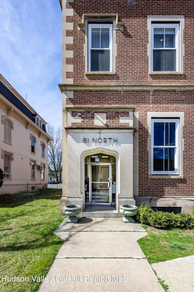 doorway to property with a yard and brick siding