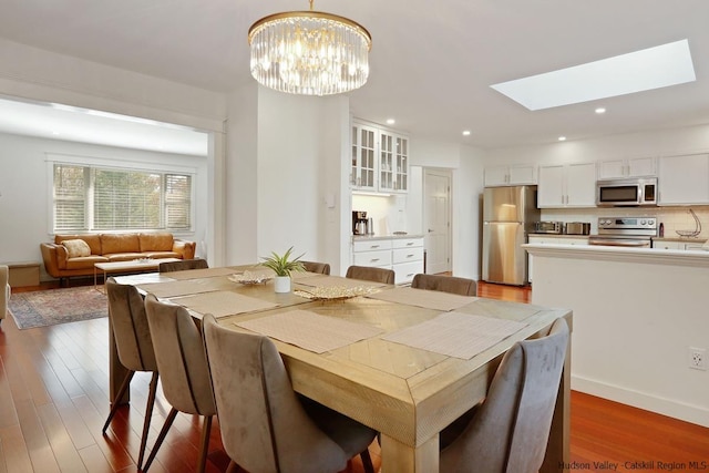 dining space featuring a chandelier, a skylight, and dark hardwood / wood-style floors