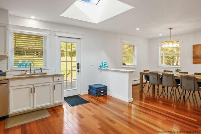 kitchen with a wealth of natural light, sink, hanging light fixtures, and light hardwood / wood-style flooring