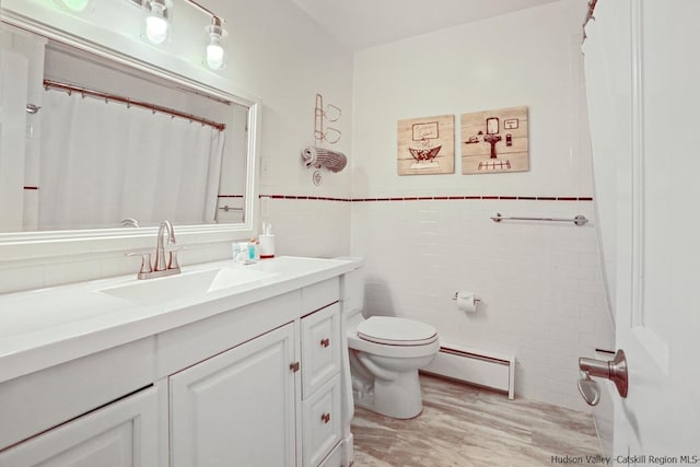 bathroom featuring vanity, toilet, baseboard heating, and tile walls