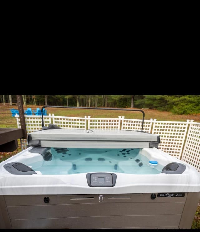 view of swimming pool with a lawn and a hot tub