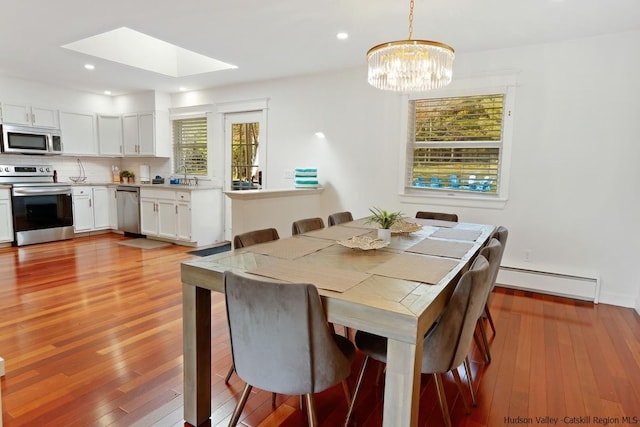 dining space featuring baseboard heating, a healthy amount of sunlight, and light wood-type flooring