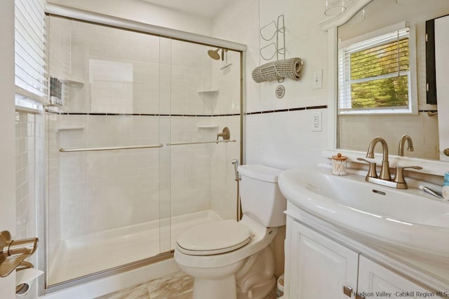 bathroom with vanity, toilet, a shower with door, and tile walls