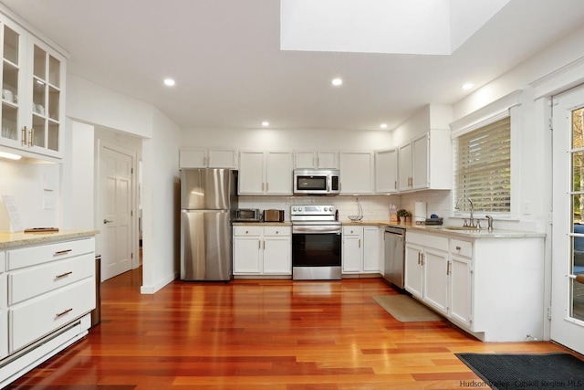 kitchen with white cabinets, appliances with stainless steel finishes, and hardwood / wood-style flooring