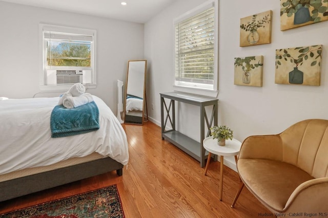 bedroom with multiple windows, cooling unit, and light hardwood / wood-style floors