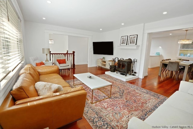 living room with a chandelier, wood-type flooring, and a wood stove