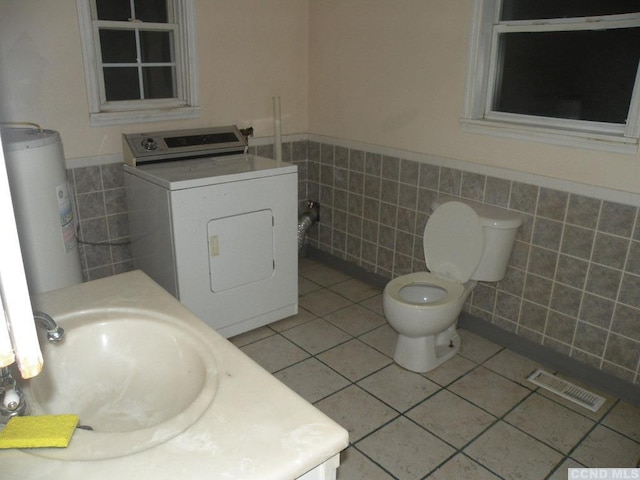 618 Bean River Rd, Pine Plains, NY 12567 - bathroom featuring washer / dryer, tile walls, water heater, a wainscoted wall, and tile patterned floors