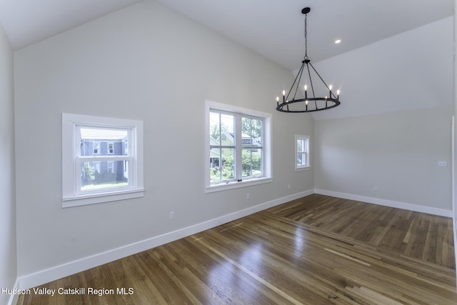 unfurnished dining area featuring high vaulted ceiling, dark hardwood / wood-style floors, and an inviting chandelier