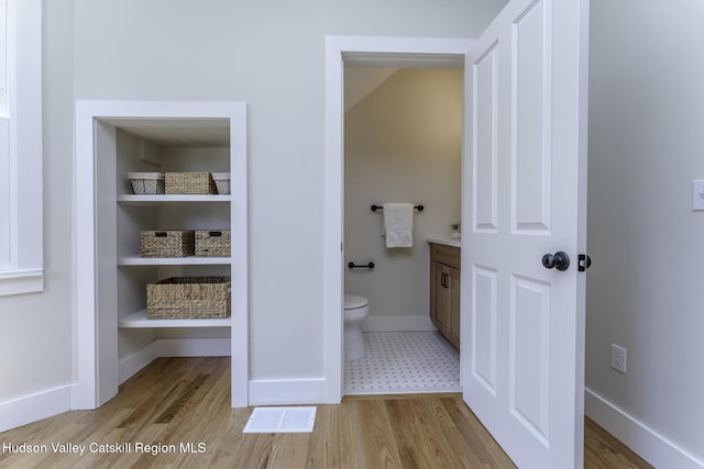 bathroom with toilet, wood-type flooring, and vanity