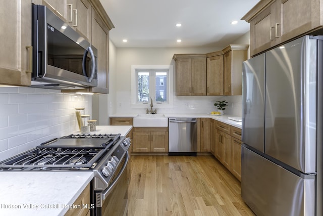 kitchen with decorative backsplash, sink, light hardwood / wood-style flooring, and stainless steel appliances