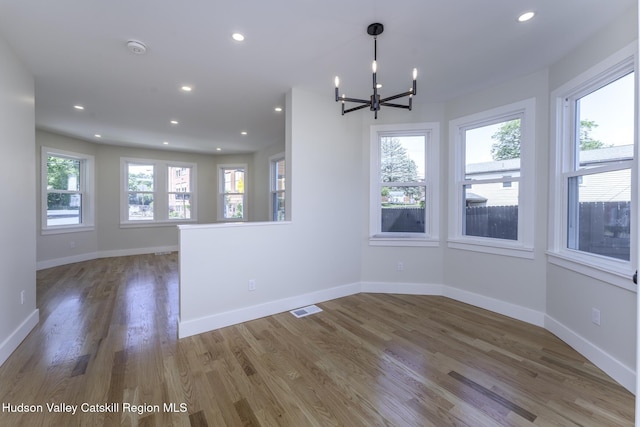 unfurnished room with hardwood / wood-style flooring and a chandelier