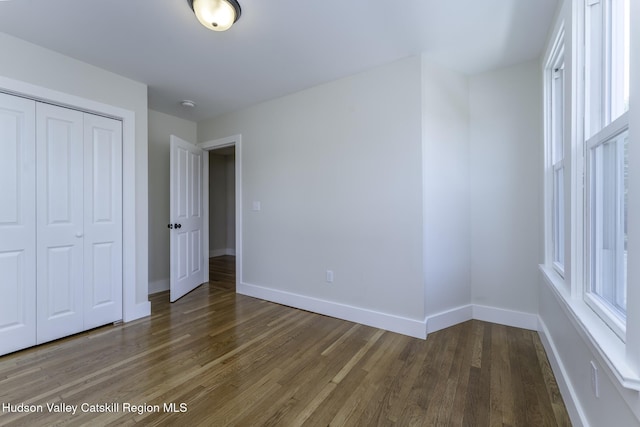 unfurnished bedroom with a closet and dark hardwood / wood-style floors