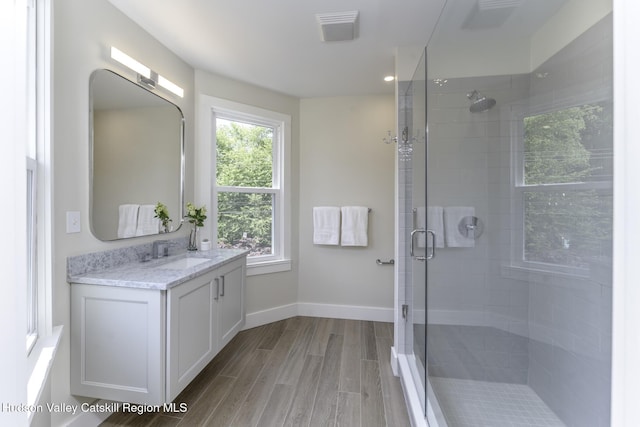 bathroom featuring wood-type flooring, a shower with door, and vanity