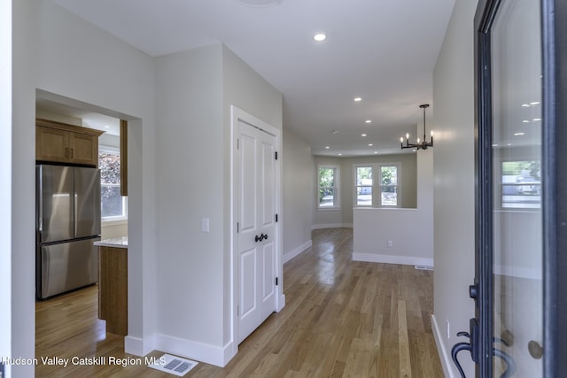 hallway featuring light hardwood / wood-style floors and a notable chandelier