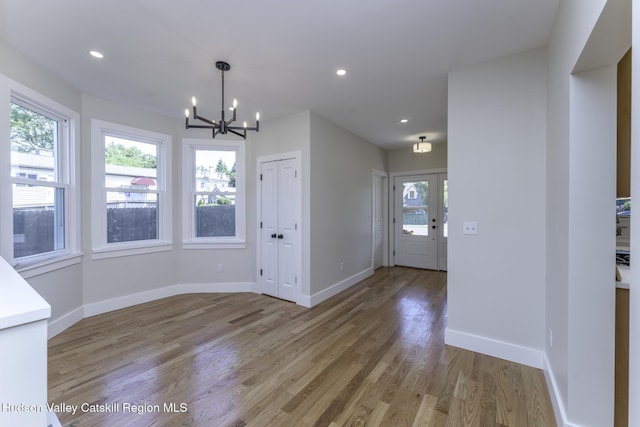 unfurnished dining area with hardwood / wood-style flooring, a wealth of natural light, and a chandelier