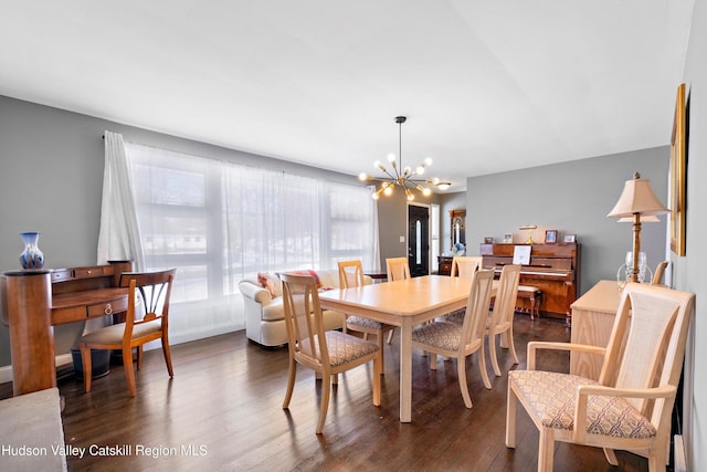 dining area with dark wood-style floors and an inviting chandelier