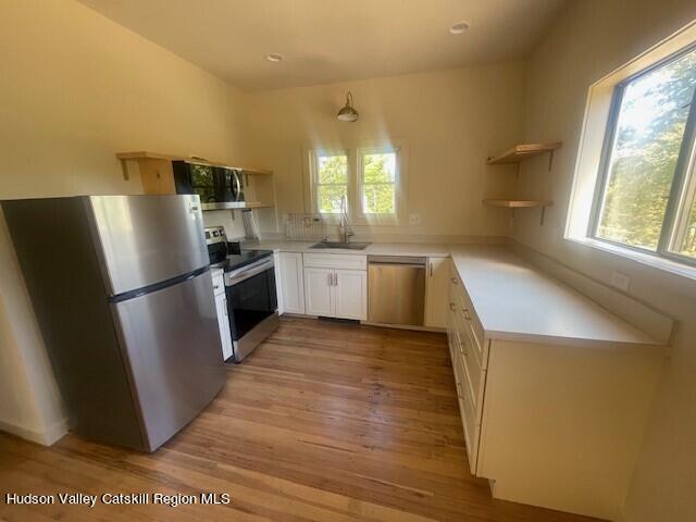 kitchen with white cabinets, stainless steel appliances, light hardwood / wood-style floors, and sink