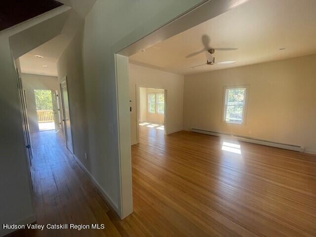 spare room featuring hardwood / wood-style floors, a baseboard radiator, plenty of natural light, and ceiling fan