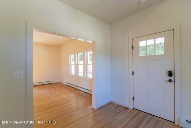 entrance foyer featuring baseboard heating, a wealth of natural light, and light hardwood / wood-style flooring