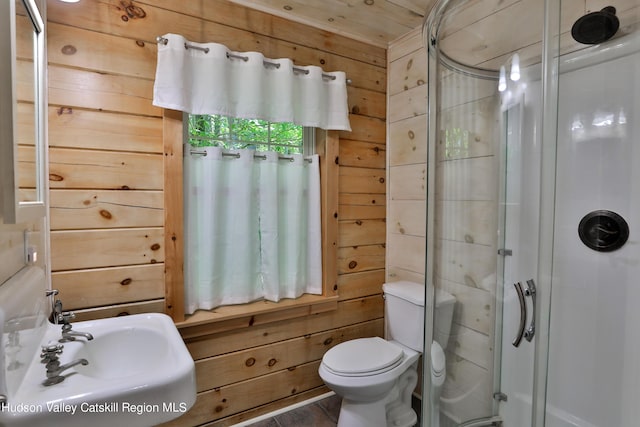 bathroom with sink, toilet, wooden walls, a shower with shower door, and hardwood / wood-style flooring