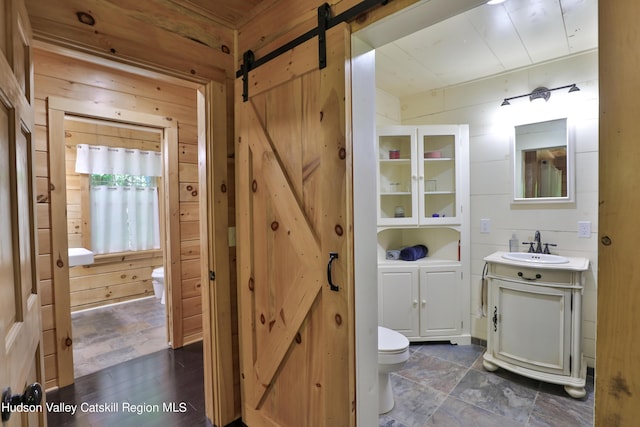 bathroom featuring wooden walls, hardwood / wood-style floors, vanity, and toilet