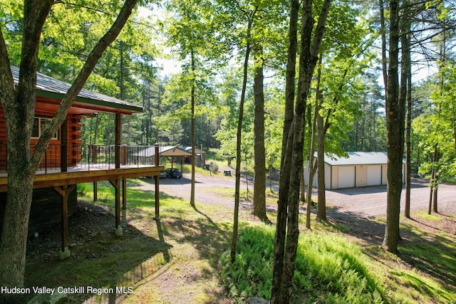 view of yard with a garage, an outbuilding, and a wooden deck