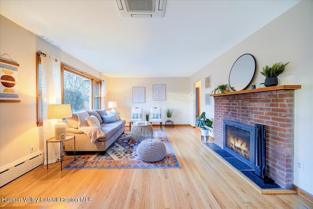 living room featuring a baseboard radiator, wood finished floors, and a fireplace