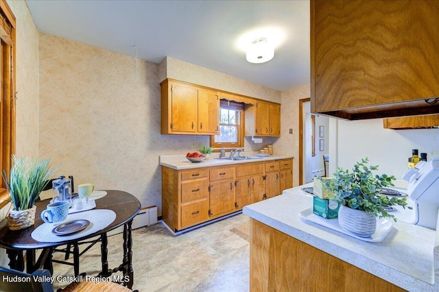 kitchen with brown cabinets, light countertops, a baseboard radiator, and a sink