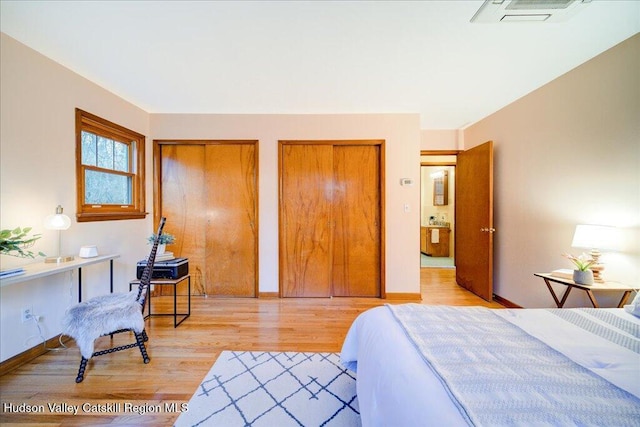 bedroom with baseboards, light wood-style flooring, visible vents, and multiple closets