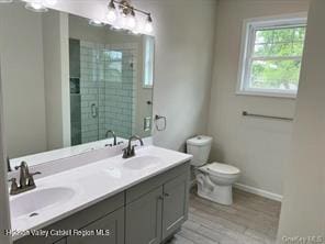 bathroom featuring hardwood / wood-style flooring, vanity, toilet, and a shower with shower door