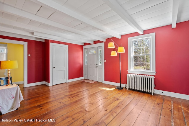 foyer featuring light wood-style flooring, beamed ceiling, radiator heating unit, and baseboards