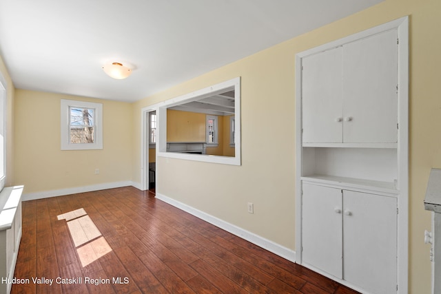 spare room featuring dark wood-type flooring and baseboards