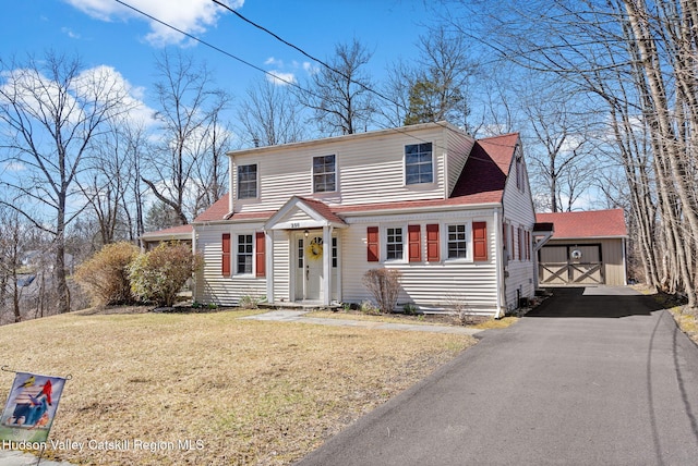view of front of house with roof with shingles, aphalt driveway, a front yard, and an outdoor structure