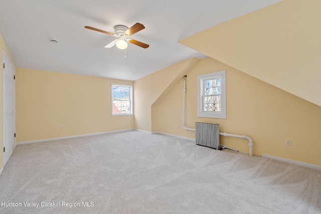 additional living space featuring baseboards, a ceiling fan, radiator, lofted ceiling, and carpet
