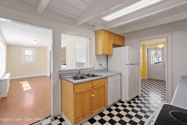 kitchen featuring beamed ceiling, white appliances, a sink, and light floors