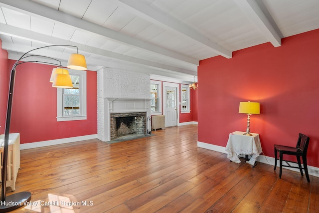 living room featuring radiator heating unit, hardwood / wood-style flooring, and beamed ceiling