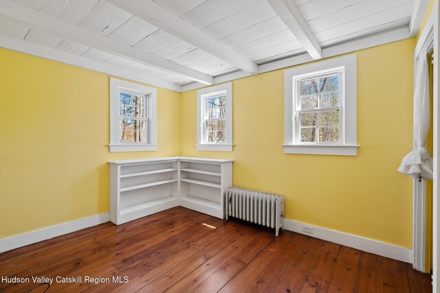 spare room featuring beamed ceiling, radiator heating unit, hardwood / wood-style flooring, and baseboards