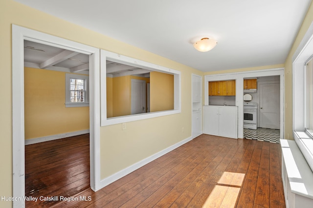 interior space with dark wood-style flooring, baseboards, and beam ceiling