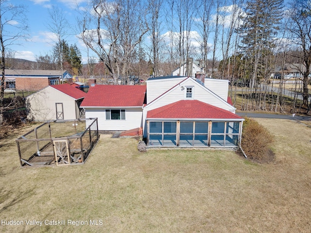 back of property with a chimney, fence, a lawn, and roof with shingles