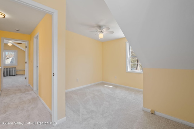 additional living space with radiator, ceiling fan, carpet, vaulted ceiling, and baseboards