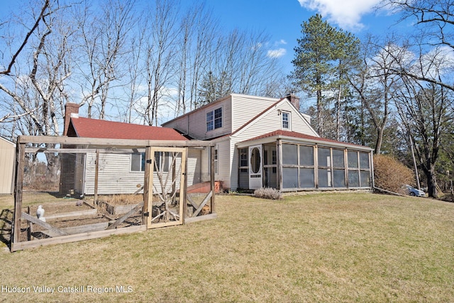 rear view of house featuring a vegetable garden, a sunroom, a yard, a chimney, and a shingled roof