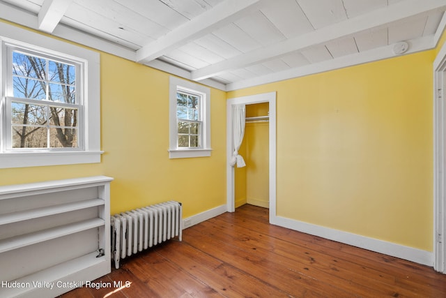 unfurnished bedroom with baseboards, hardwood / wood-style floors, radiator, beam ceiling, and wooden ceiling