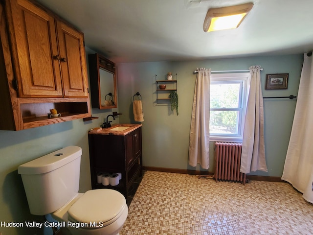bathroom with tile patterned floors, vanity, baseboards, radiator, and toilet