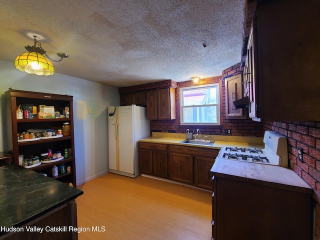 kitchen featuring ventilation hood, a textured ceiling, a sink, and white appliances