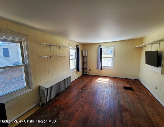 unfurnished living room featuring wood-type flooring, visible vents, and radiator
