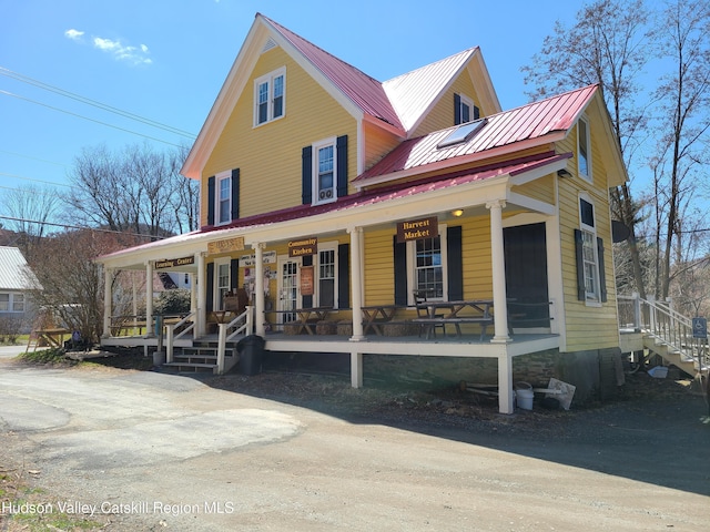 farmhouse with covered porch, stairs, and metal roof