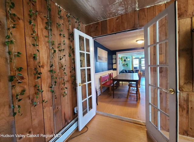 interior space featuring a baseboard radiator, wood finished floors, and french doors