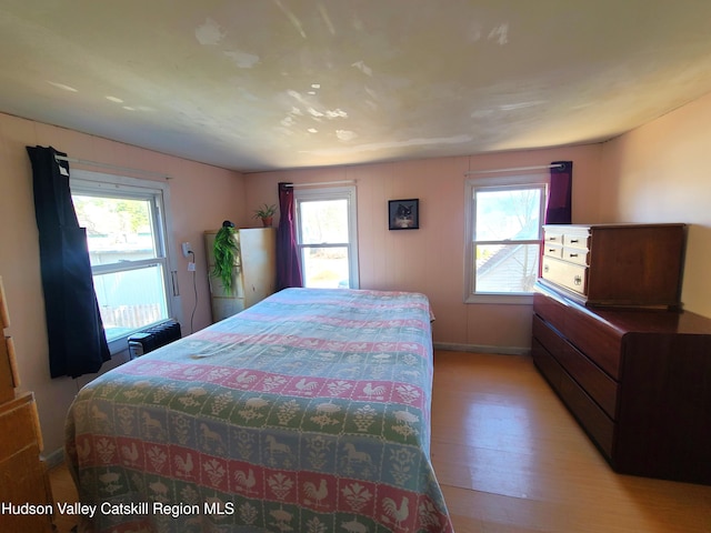 bedroom featuring light wood-style flooring, baseboards, and multiple windows