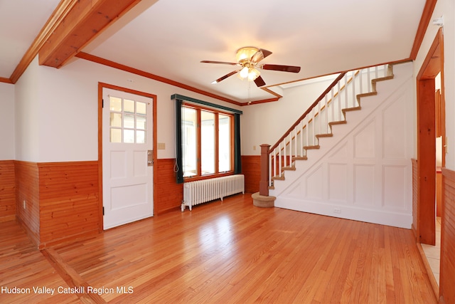 foyer with light wood-style floors, stairway, wainscoting, radiator, and crown molding